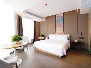 A hotel room with a bed, bedside table, chair, and a small table with a plant. - Mercure Huhhot Economic Zone (Hohhot)