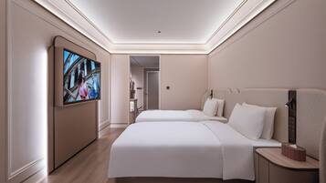Habitación de hotel con dos camas, un televisor montado en la pared y una mesita de noche con lámpara.
