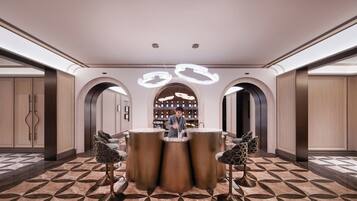 Um lobby moderno com área de bar central, portas em arco e piso estampado.