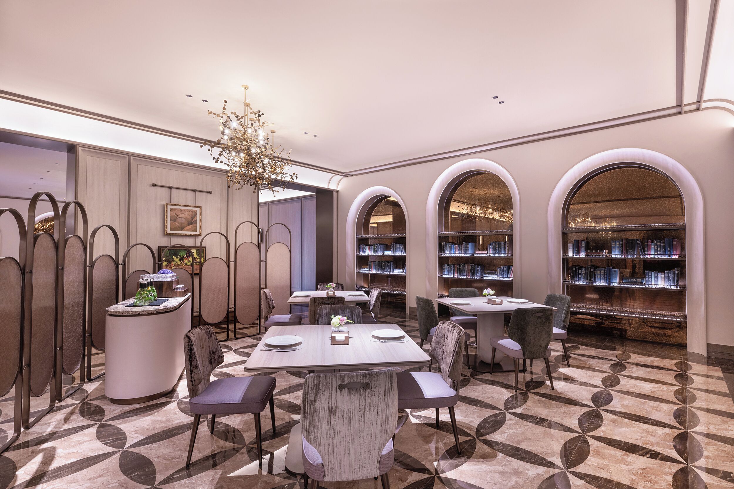 A modern interior with tables and chairs, a decorative light fixture, and bookshelves.
