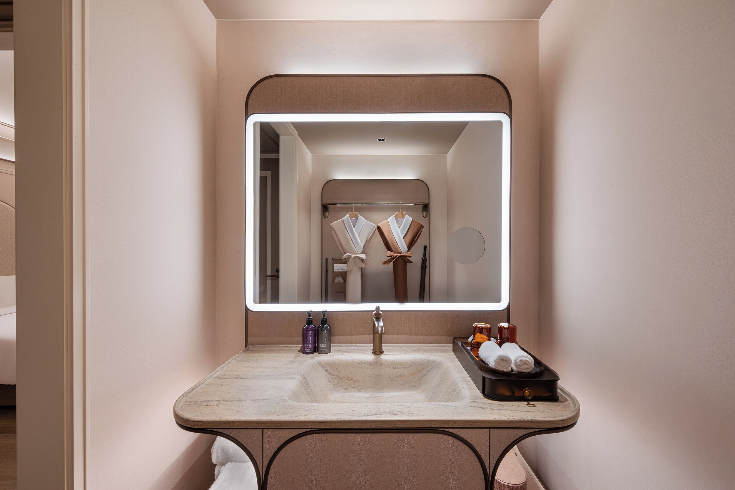A bathroom with a large mirror, a sink, and a towel rack.