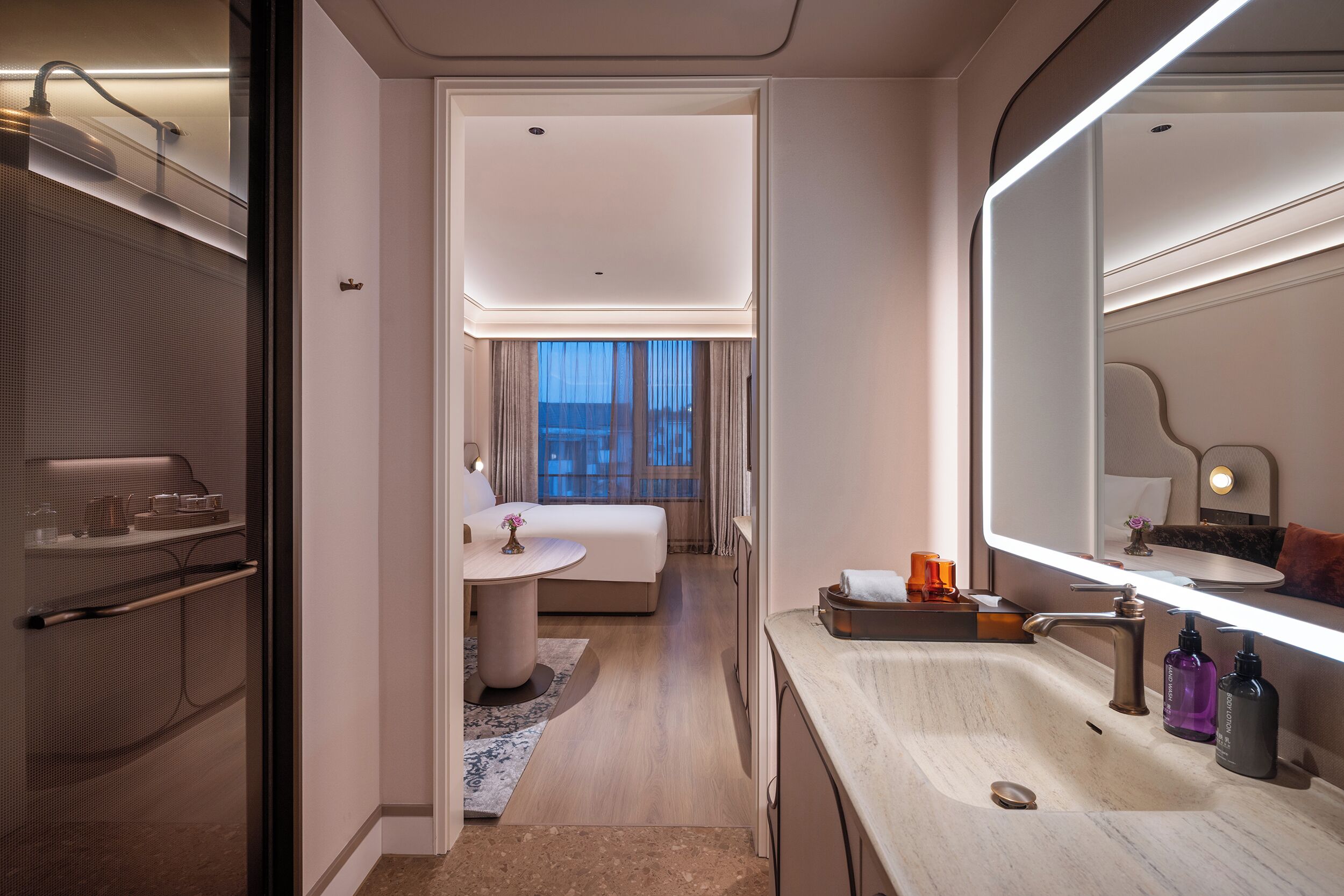 A modern hotel bathroom with a vanity, sink, and mirror.
