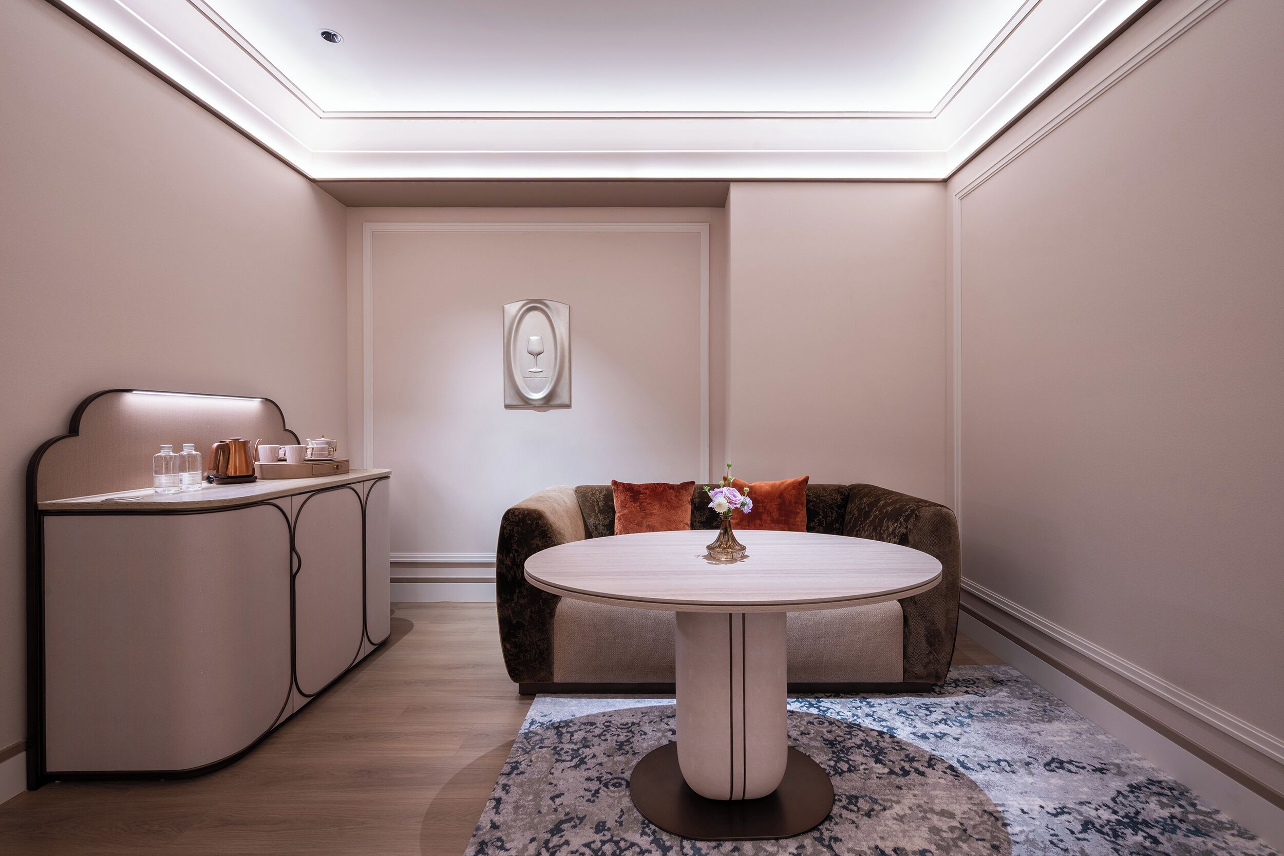 Une pièce comprenant une table ronde, un canapé, un meuble et un tapis à motifs.