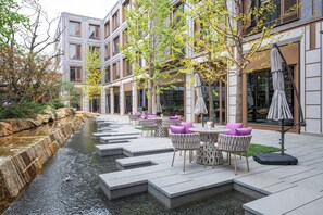 Un patio moderno al aire libre con asientos escalonados, una fuente pequeña y mobiliario exterior.