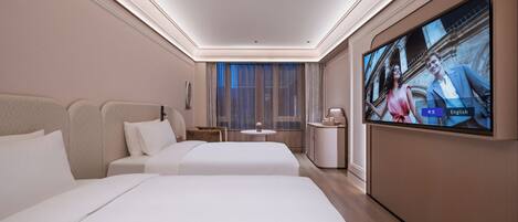 A hotel room with two beds, a TV, a small table, and a window with curtains.