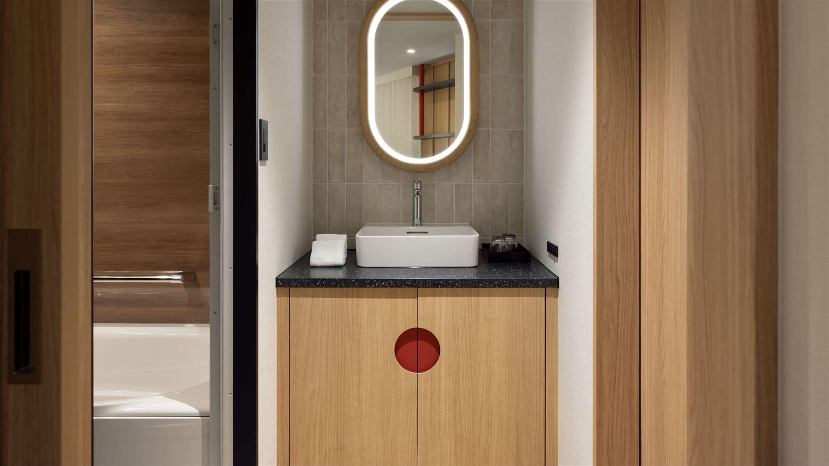 A bathroom with a white sink, a mirror with a light, and wooden cabinets.