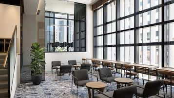 A modern indoor space with large windows, seating arrangements, and a staircase.