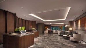 Een moderne lobby met een receptiebalie, zithoek en grote ramen.