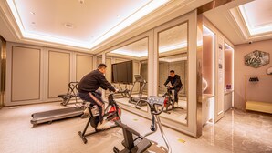 Uma academia com equipamentos de exercício, um espelho grande e uma televisão.