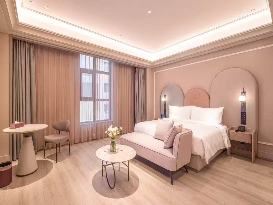 Ein Hotelzimmer mit Bett, Nachttisch, Lampe und einem kleinen Tisch mit Blumen.