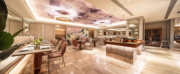 Un'ampia hall dell'hotel con una lunga reception, comodi posti a sedere e un soffitto decorativo.