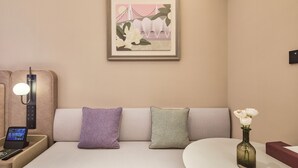 Een hotelkamer met een bank, een nachtkastje met een lamp, een afstandsbediening en een lijst aan de muur.