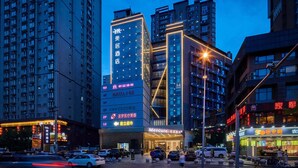 Um hotel com v ários andares, entrada em destaque e sinalização iluminada.