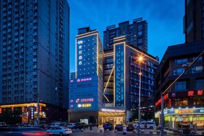 Een hotel met meerdere verdiepingen, een opvallende ingang en verlichte signage.