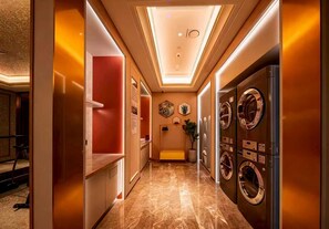 Une buanderie avec un sol en marbre, deux machines à laver et un plafond doté d’un éclairage encastré.