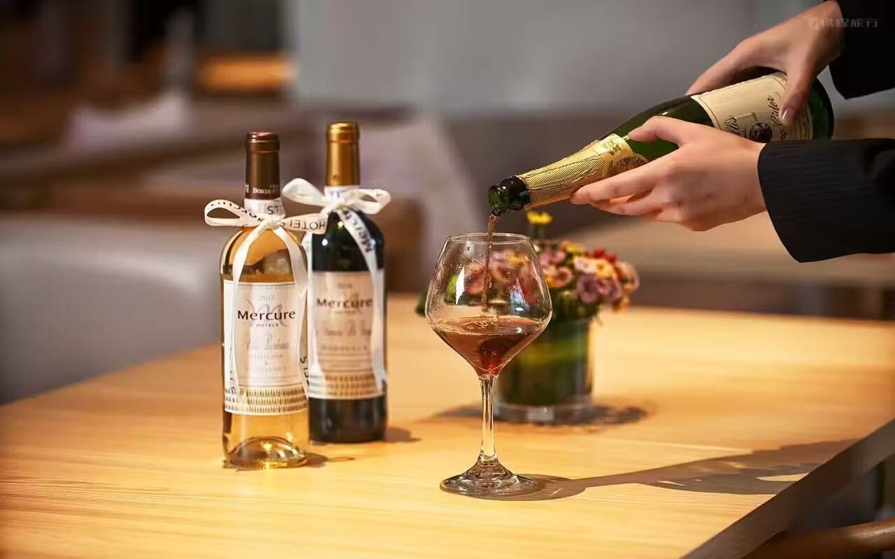 A bottle of wine being poured into a glass on a wooden table.