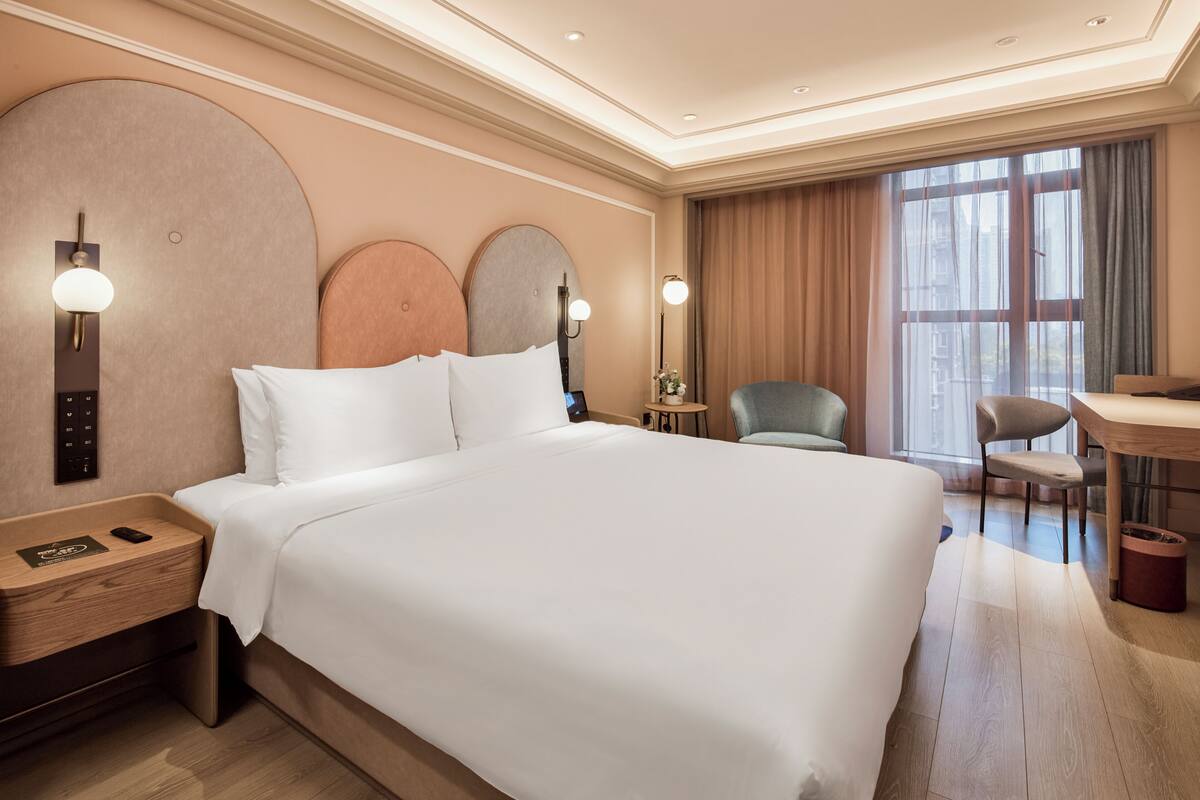 Een hotelkamer met een groot bed, nachtkastjes, een bureau en een stoel.