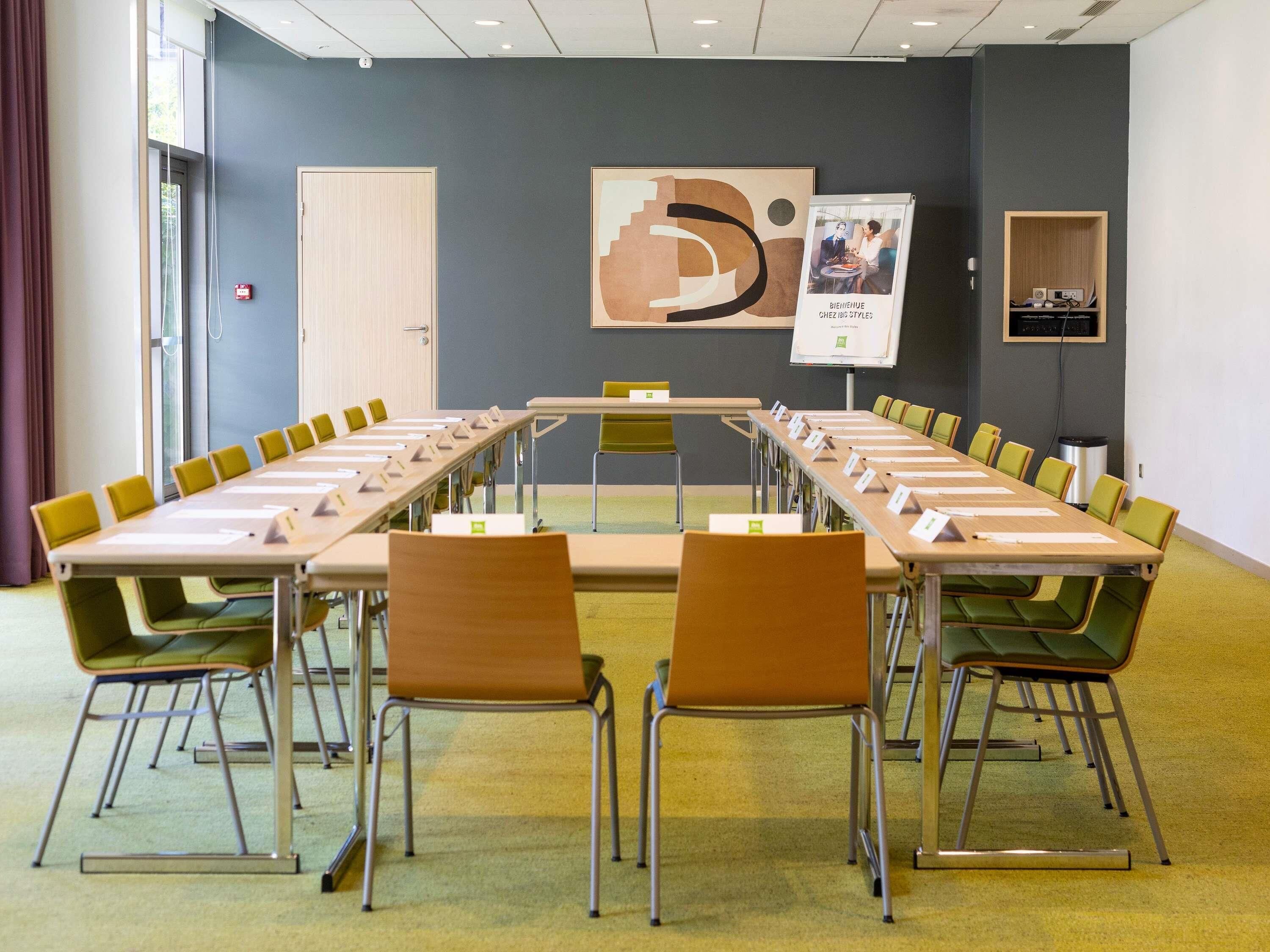 Ein Konferenzraum mit einem langen Tisch, Stühlen, einer Whiteboard-Tafel und einer Tür.