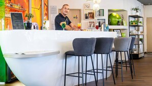 A modern bar area with a curved counter, black bar stools, and pendant lighting. - Ibis Styles Troyes Centre (Troyes)