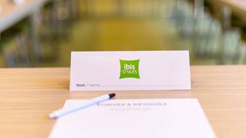 Tarjeta de presentación con el logotipo de 'ibis Styles' sobre una mesa de madera.