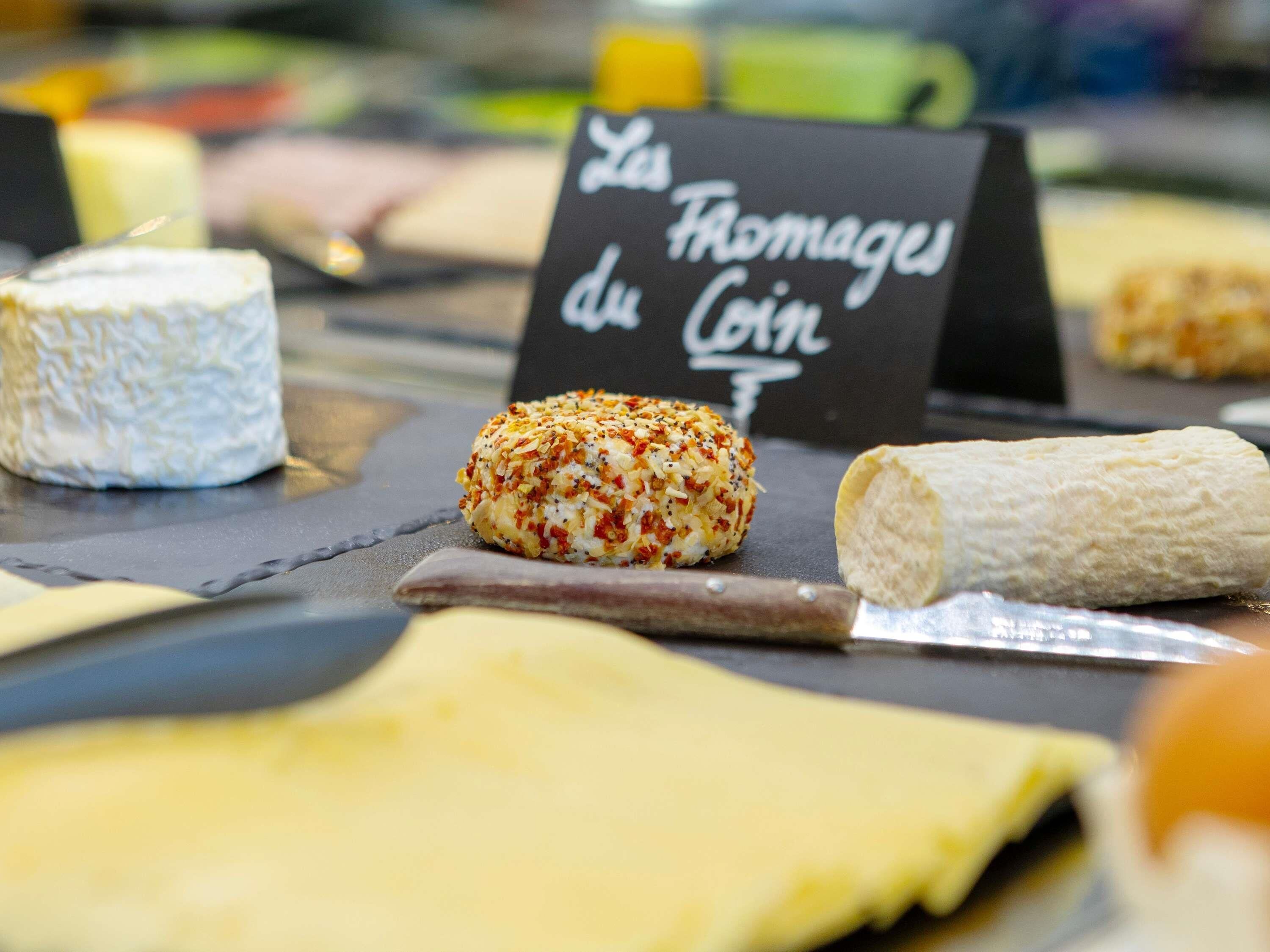 Eine Käseauslage mit einem Schild, auf dem 'Les Fromages du Coin' steht.
