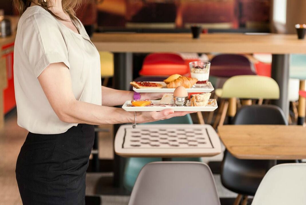 Een persoon draagt een dienblad met eten.