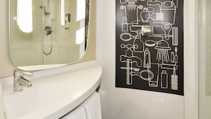A bathroom with a white sink, a mirror, and a black wall with white bathroom icons. - Ibis Troyes Centre (Troyes)