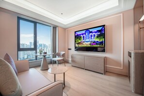 A modern living room with a large TV, a sofa, a small table, and a view of the city through large windows. - Mercure Chongqing Times Paradise Walk (Chongqing)