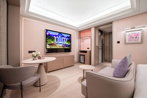 Une chambre d’hôtel moderne équipée d’une télévision à écran plat, d’un canapé, d’une petite table et d’un meuble de rangement.