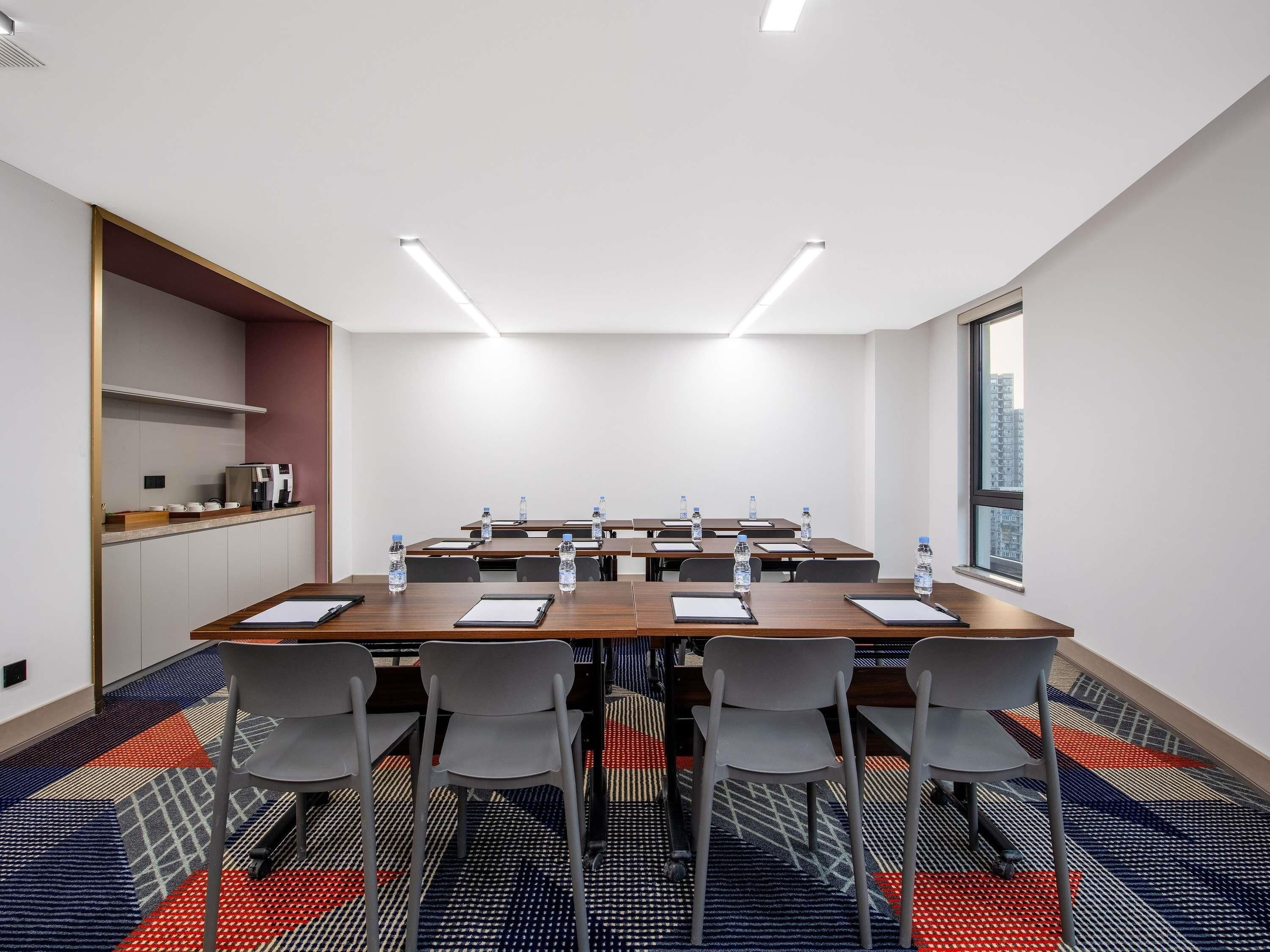 A conference room with a long table, chairs, water bottles, and a coffee station.