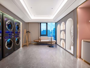 Une chambre d’hôtel avec vue sur la ville, un lave-linge, un canapé et une petite table.