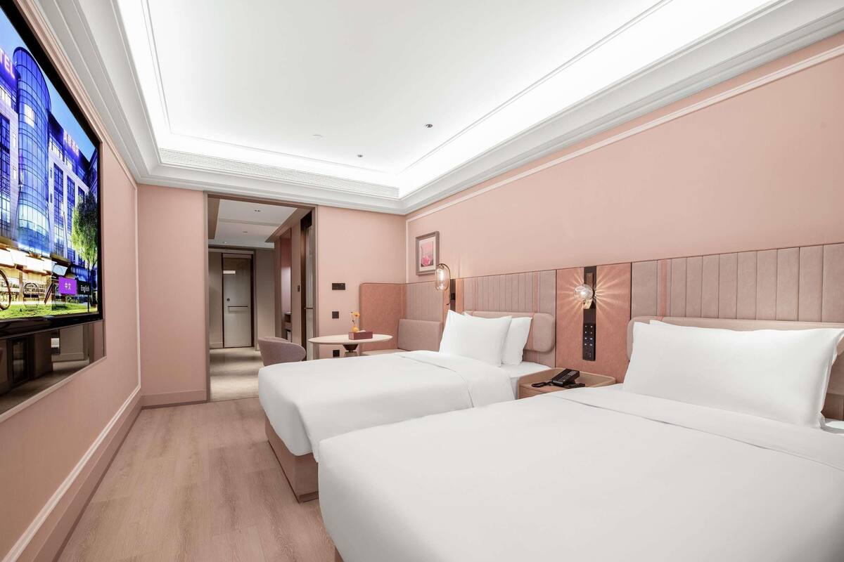 Habitación de hotel con dos camas, televisión, escritorio y mesita de noche.