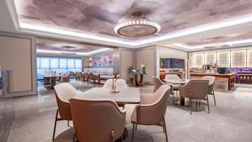 A spacious dining area with marble flooring, modern furniture, and a ceiling with a unique design.