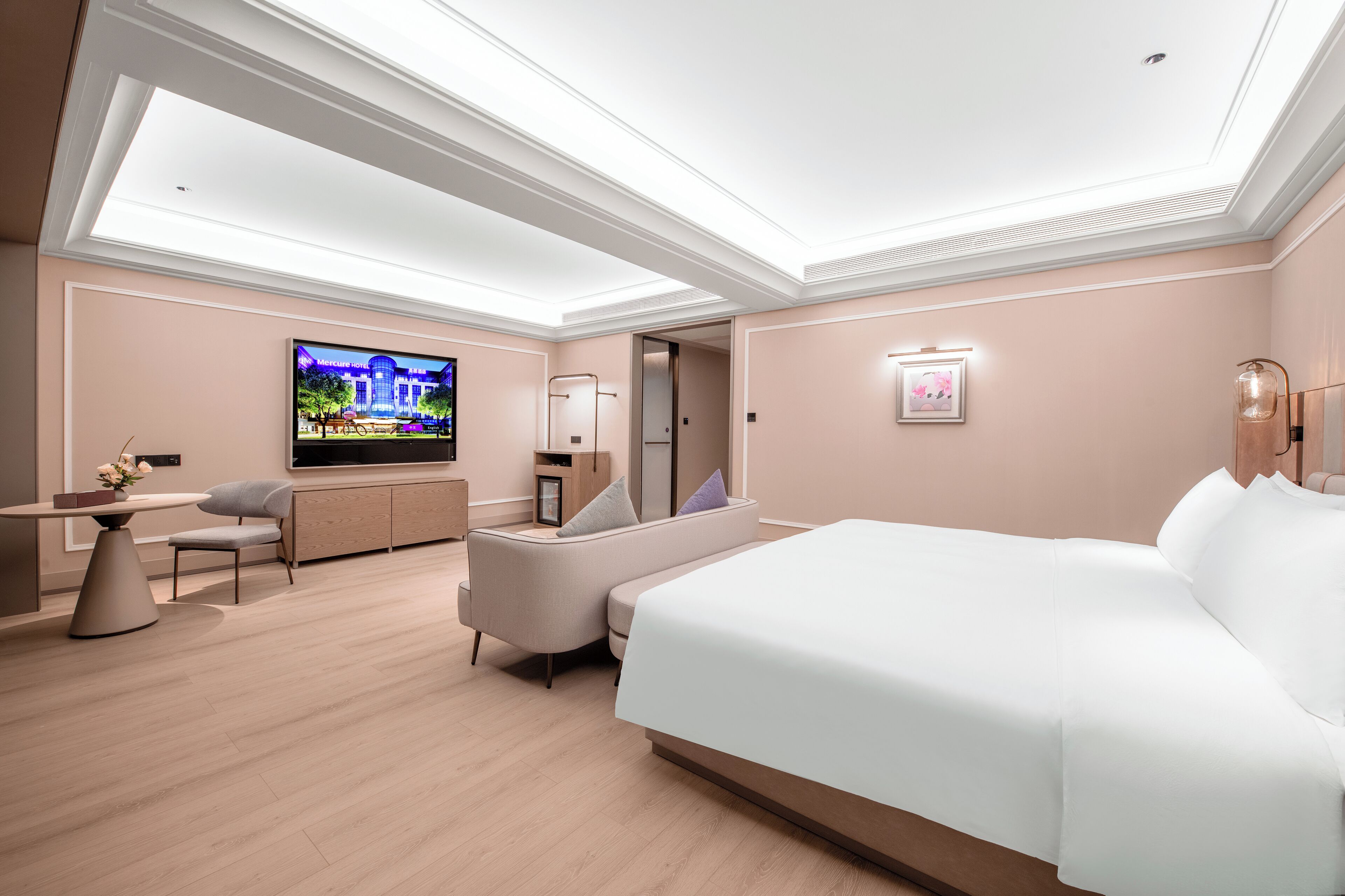 Una habitación de hotel moderna con una cama grande, un televisor, un sofá y un área de comedor.