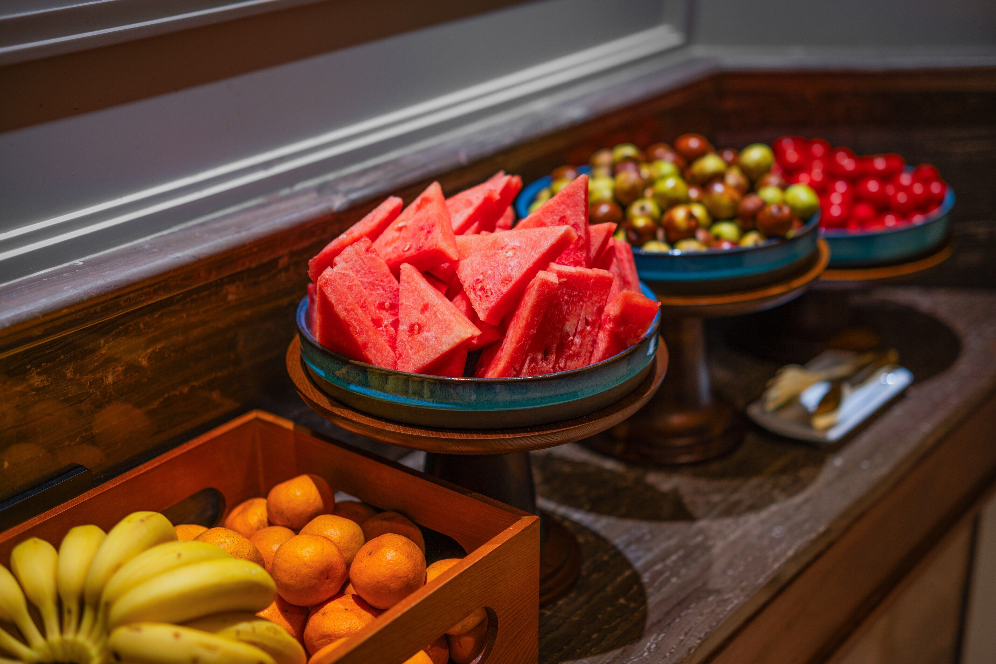 A buffet with various fruits including watermelon, apples, and oranges.