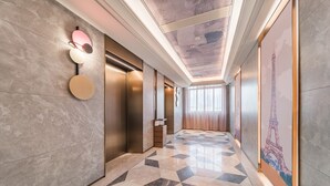 A modern hallway with a geometric patterned floor, a wall-mounted light fixture, and a large poster of the Eiffel Tower. - Mercure Zhangjiajie Tianmen Mountain (Zhangjiajie)
