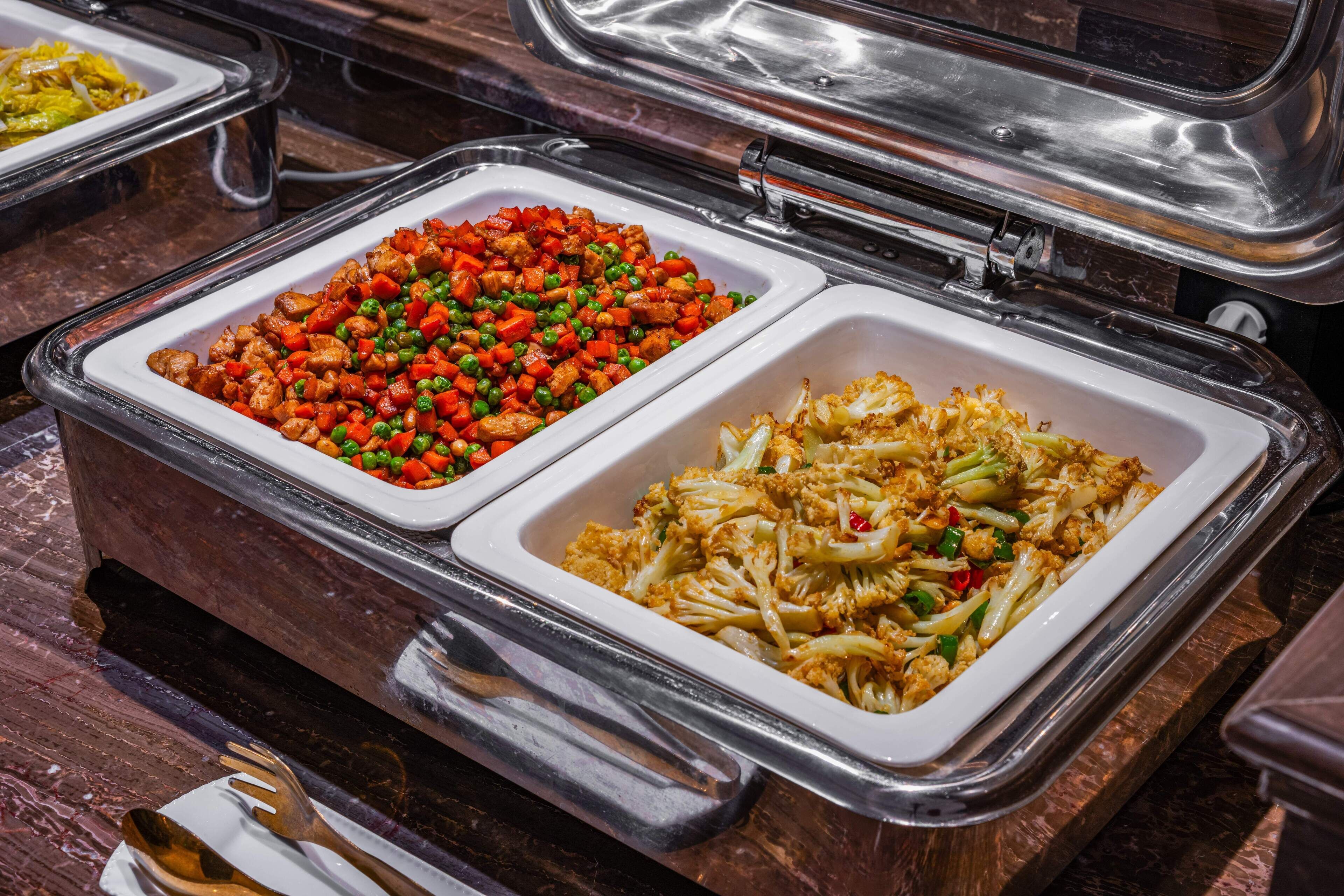 A buffet with two large white trays containing various dishes.