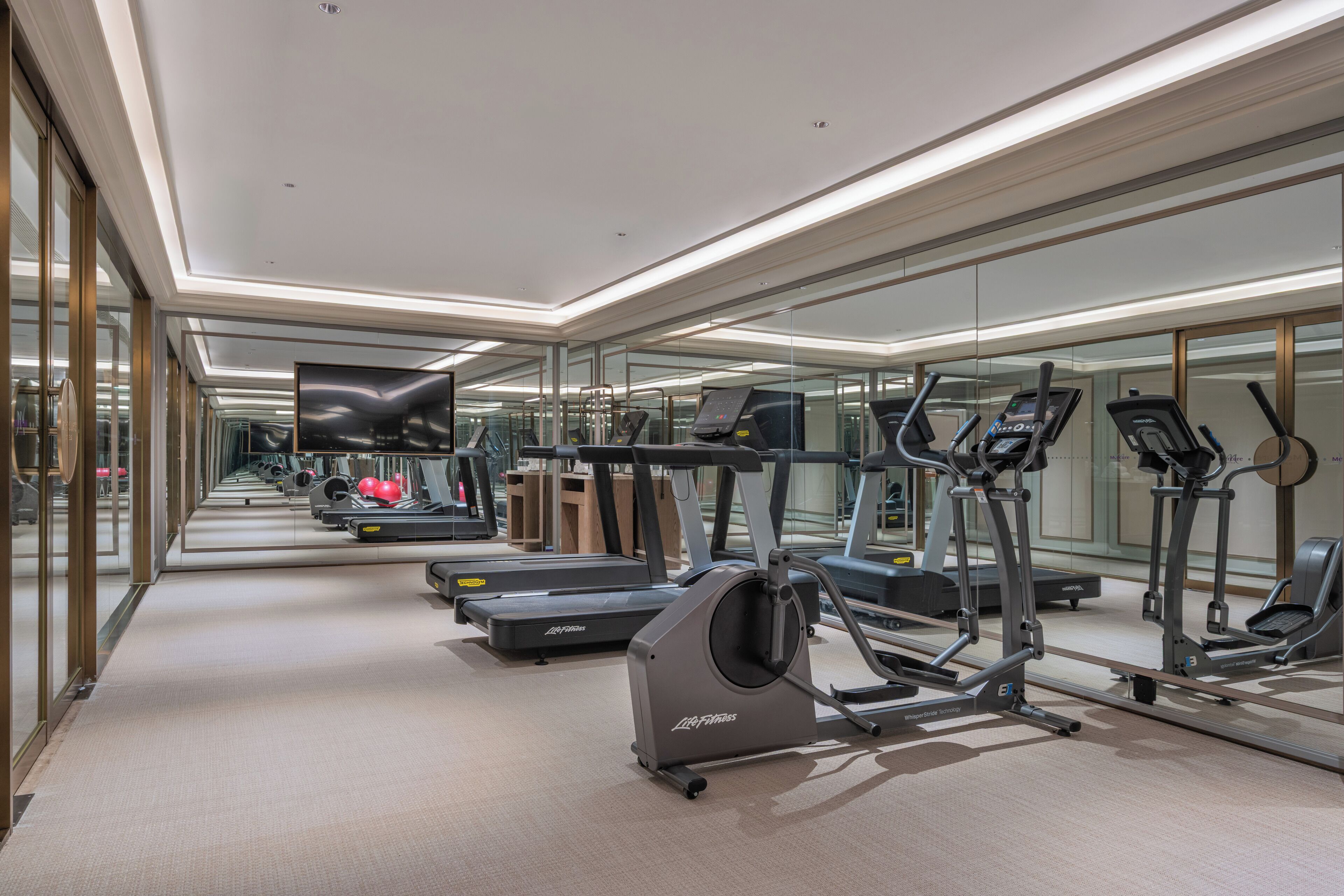 Un gimnasio moderno con paredes de espejo, cintas de correr y elípticas.