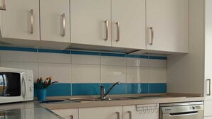 A kitchen with white cabinets, a microwave, a dishwasher, and a blue backsplash. - The Sea Outside (Alghero)