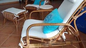 A room with wicker lounge chairs, a blue sofa, and a dining table. - The Sea Outside (Alghero)
