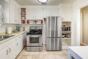 A kitchen with white cabinets, stainless steel appliances, a microwave, and a toaster.