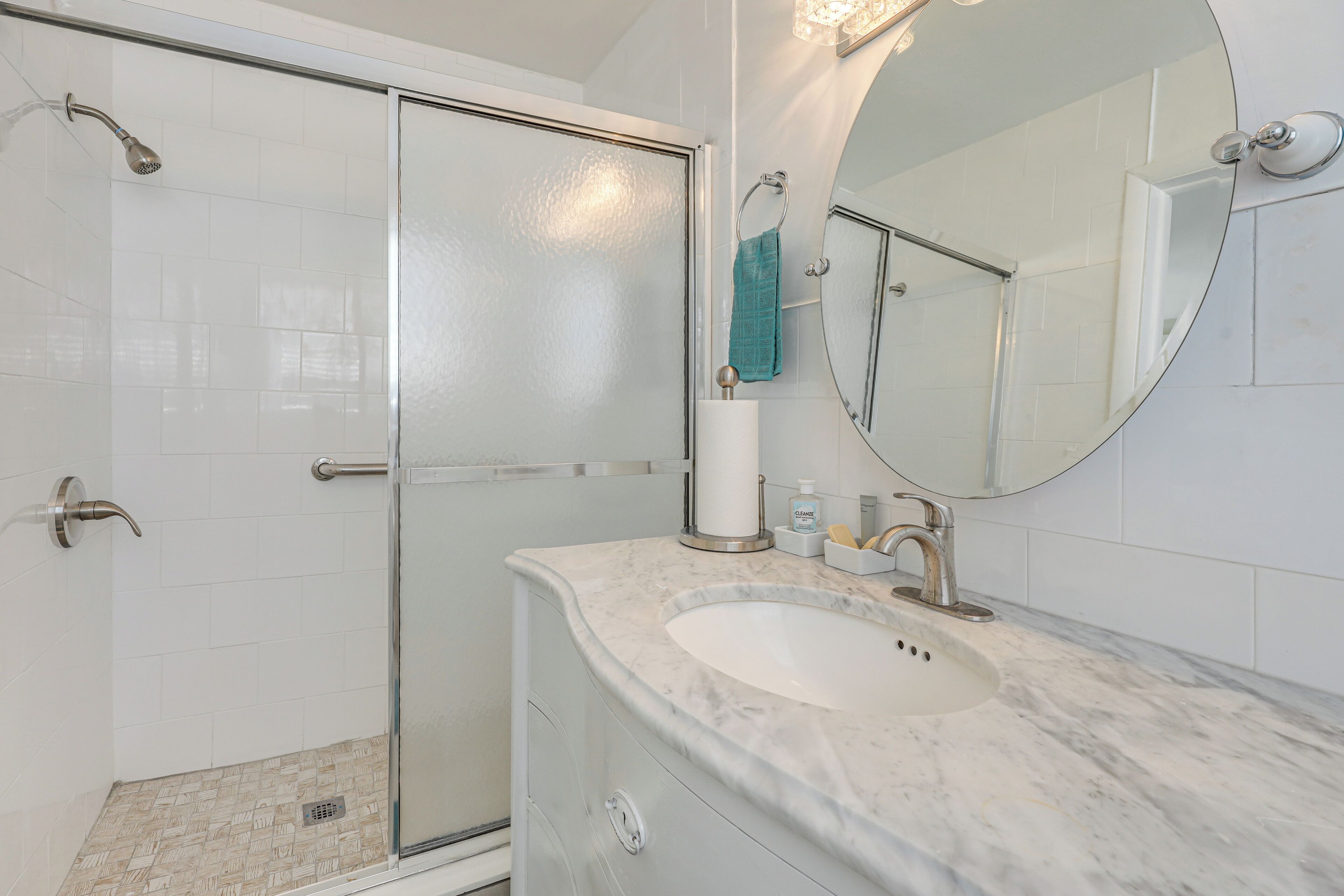 Een moderne badkamer met een glazen douchecabine, een marmeren wastafel en een grote spiegel.