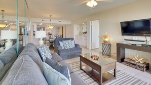 A living room with a sofa set, a glass coffee table, a television, and a ceiling fan. - 2BR Gulf-view Resort Condo: Suntide III - Unit 607 (South Padre Island)
