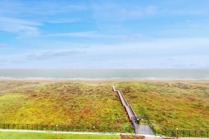 Un paisaje costero con una pasarela de madera que conduce a la playa.