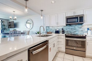 A modern kitchen with white cabinetry, a stainless steel dishwasher, a double oven, and a microwave. - Gulf-view Condo w/ Perks: Suntide III - Unit 205 (South Padre Island)