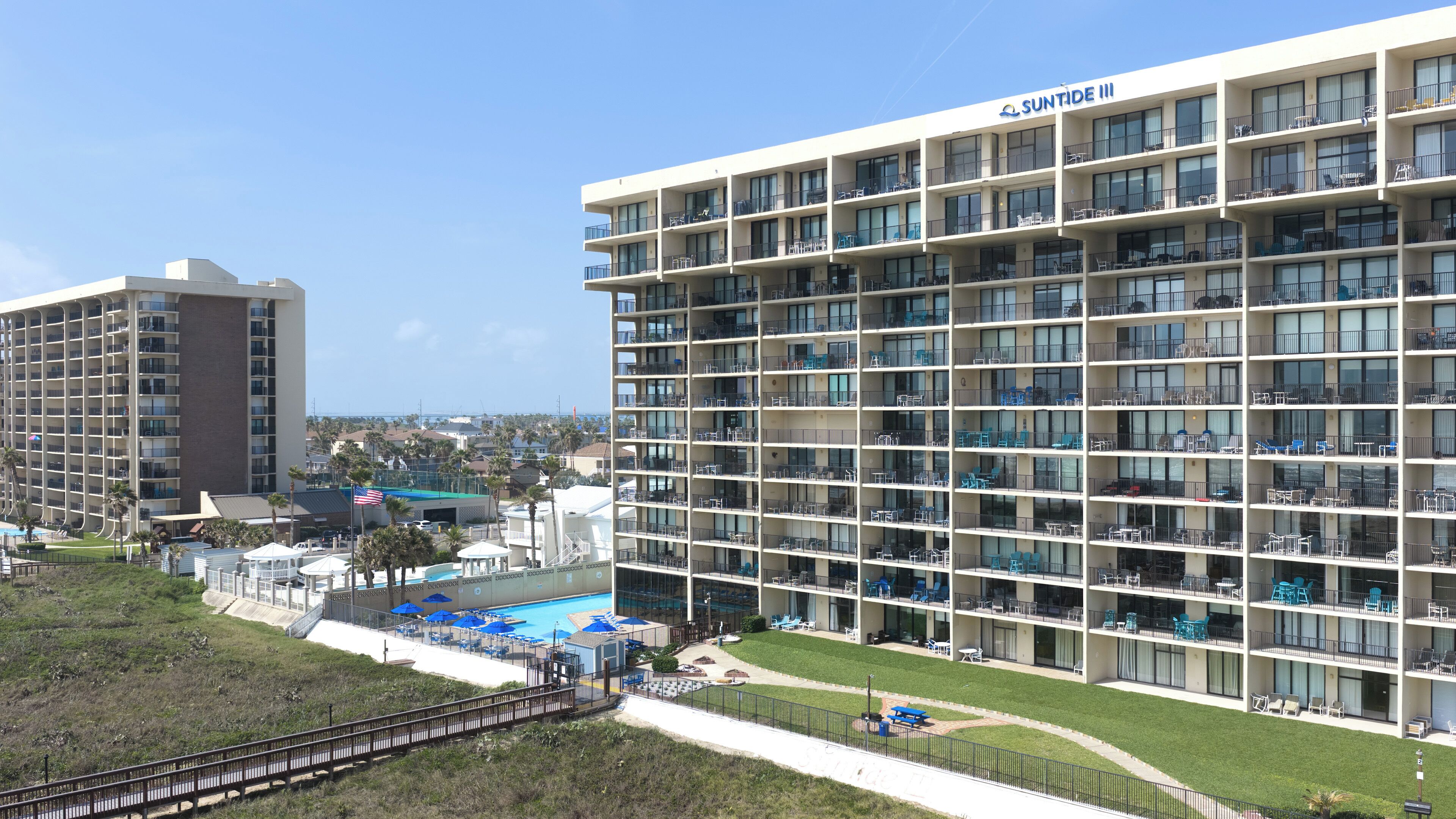 Un hôtel à plusieurs étages, doté de balcons, d’une piscine et offrant une vue sur les environs.