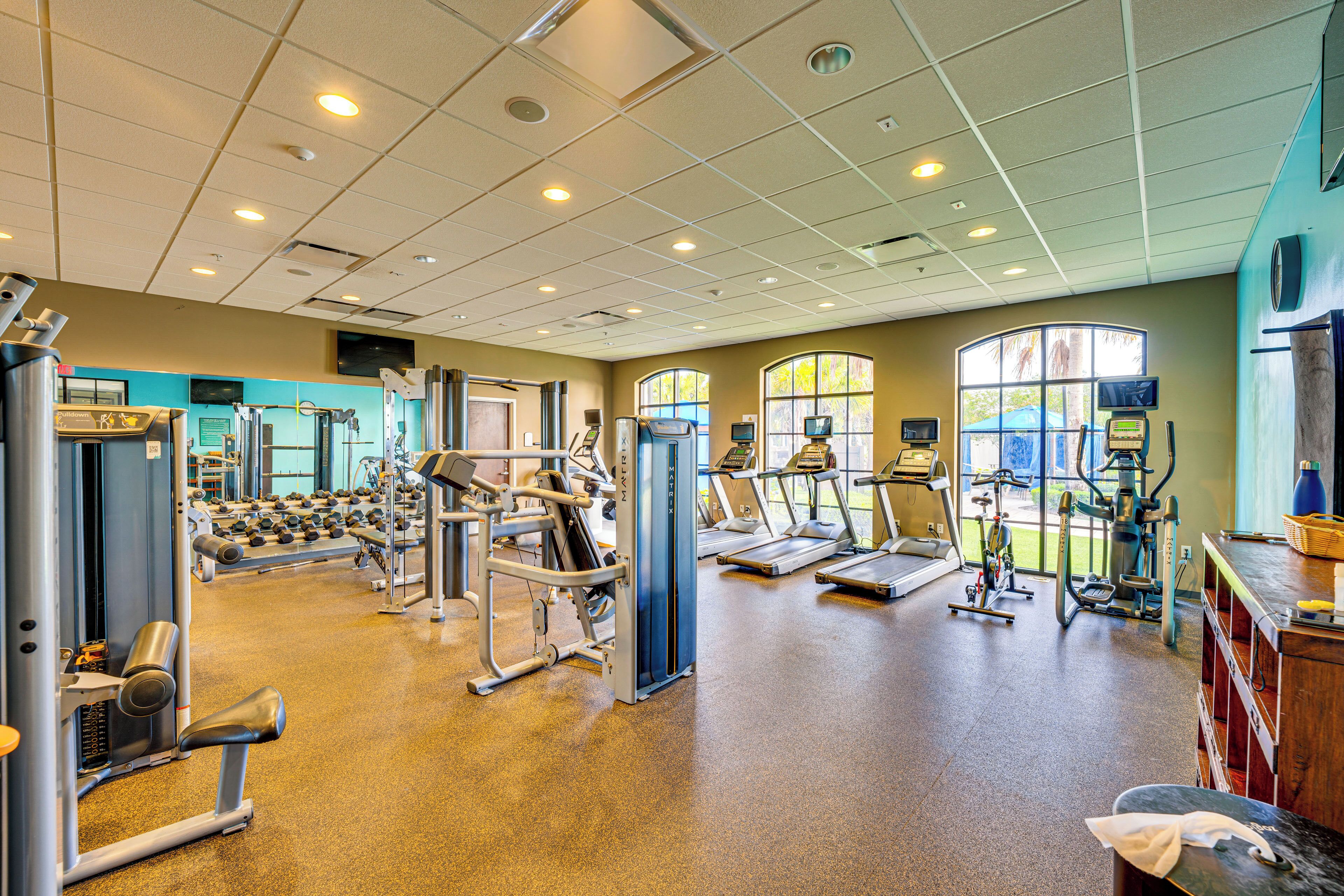 Une salle de sport équipée de machines de cardio, de postes d’entraînement en force et de divers appareils d’exercice.