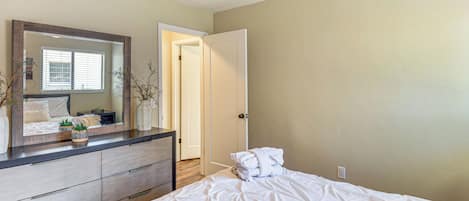 A bedroom with a bed, a dresser, a mirror, and a ceiling fan.