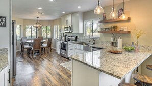 A modern kitchen with granite countertops, stainless steel appliances, and pendant lighting. - Coastal Pine Lakes Golf Club Getaway: Pets Welcome (Palm Coast)