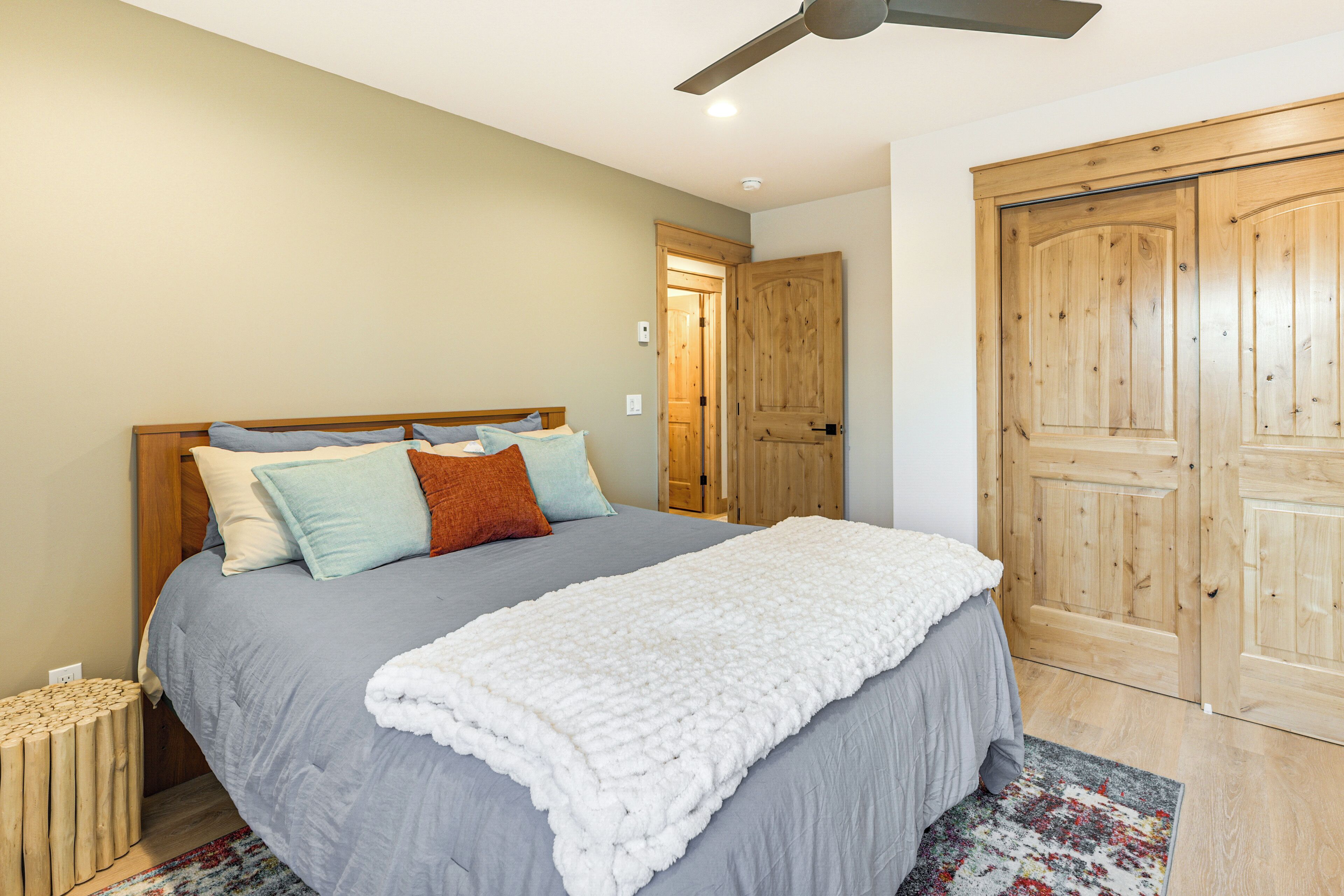 A bedroom with a bed, wooden wardrobe, and a ceiling fan.